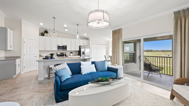 Sala de estar moderna com um sofá azul, mesa de centro branca e vista para um campo de golfe pelas portas de correr de vidro.