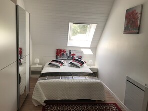 Une chambre à coucher avec un lit, des tables de chevet, une fenêtre et un tableau au mur.