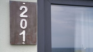 A door with a number plaque '201' and a view of the sea through a glass door. - Assos No9 Hotel (Ayvacik)
