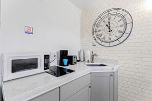 Una kitchenette equipada con microondas, tostadora, cafetera y lavaplatos.