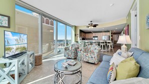 A spacious living area with a large window, a sofa, a coffee table, and a television.