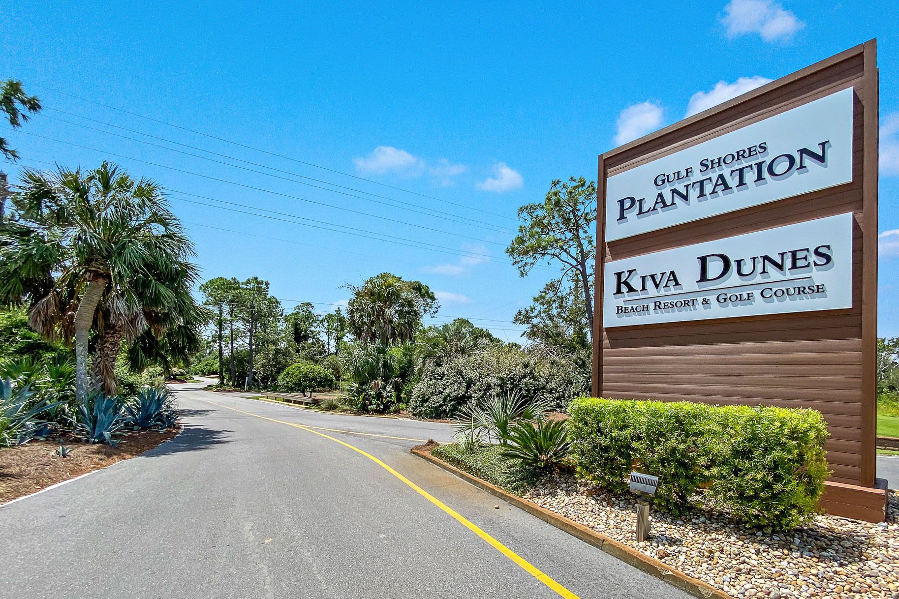Une route menant à un panneau indiquant l’accès à Gulf Shores Plantation et au complexe hôtelier et terrain de golf Kiva Dunes Beach Resort.