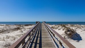 Una passerella di legno che conduce a una spiaggia, con cielo sereno.