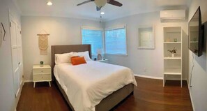 Relax in this serene bedroom with a large bed, ceiling fan, and wall-mounted TV.