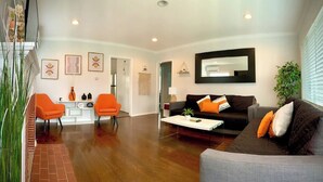 A modern living room with a sofa, two orange chairs, a coffee table, and a large mirror on the wall. - Bright 2 Bedroom Cozy HOUSE! Pasadena/Alhambra Prime Location! Dogs OK! (Alhambra)