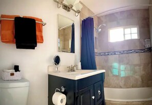 Ein Badezimmer mit Toilette, Waschbecken, Spiegel und Dusche.