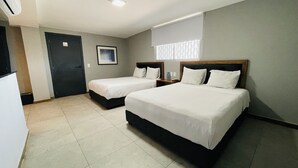 Ett hotellrum med två sängar, ett skrivbord, en stol, en dörr och ett fönster med persienner.