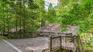 Uma cabana isolada com um deck de madeira, rodeada por uma floresta densa.