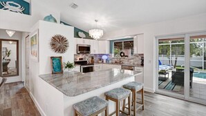 A modern kitchen with a central island, white cabinets, and a view of the backyard.