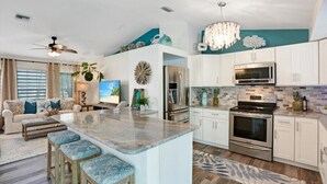 A modern kitchen with white cabinets, stainless steel appliances, and a central island.