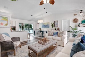 A spacious living room with a white sofa, a coffee table, and a dining area with a glass-top table and chairs. - Heated Saltwater Pool & Hot Tub Guest FAVE (Cape Coral)