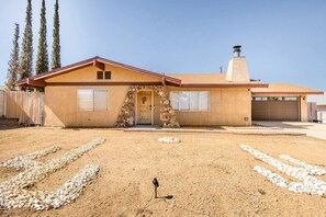 A single-story house with a stone entrance, a garage, and a clear driveway. - Tortoise Oasis - Hot tub, Shuffleboard, & More! (Yucca Valley)
