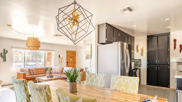 A modern kitchen with a dining area, featuring a wooden table, patterned chairs, and a refrigerator.