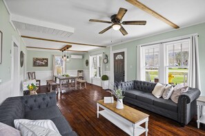 A spacious living room with a dark grey sofa, a wooden coffee table, and a ceiling fan.
