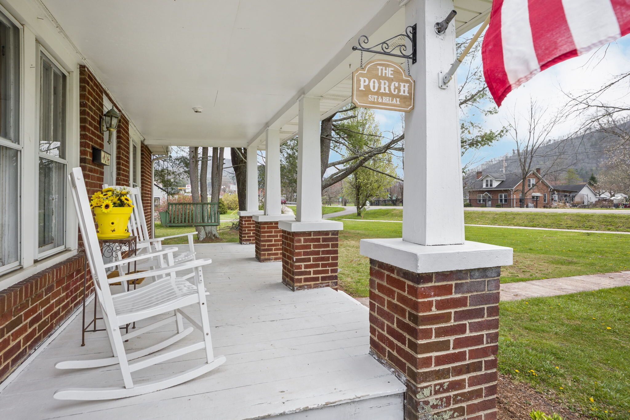 A porch with a rocking chair and a sign that reads 'The Porch Sit & Relax'.