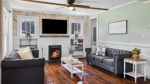 A living room with a fireplace, two sofas, a coffee table, and a ceiling fan. - Charming 4 bedroom farmhouse with large backyard for entertaining! (Mountain City)