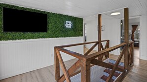 A modern interior with a green wall, a flat-screen TV, and a wooden staircase. - Charming 4 bedroom farmhouse with large backyard for entertaining! (Mountain City)