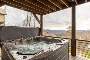 Un jacuzzi en una terraza de madera con vistas a las montañas.