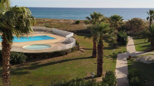 Ein Pool mit Blick auf den Ozean, umgeben von Palmen und einem Weg.