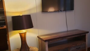 Huoneessa on puinen TV-taso, lamppu ja seinälle asennettu litteänäyttöinen televisio.