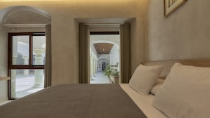 A hotel room with a large bed, a view of a courtyard through an open door, and a framed picture on the wall. - Casa Quiote Hotel Boutique City Center based - Adults Only (Oaxaca)