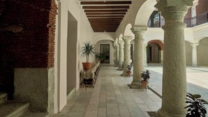 A corridor with stone columns, a brick wall, and potted plants. - Casa Quiote Hotel Boutique City Center based - Adults Only (Oaxaca)