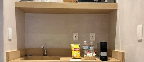 A compact kitchenette with a microwave, a small sink, and a refrigerator stocked with beverages.