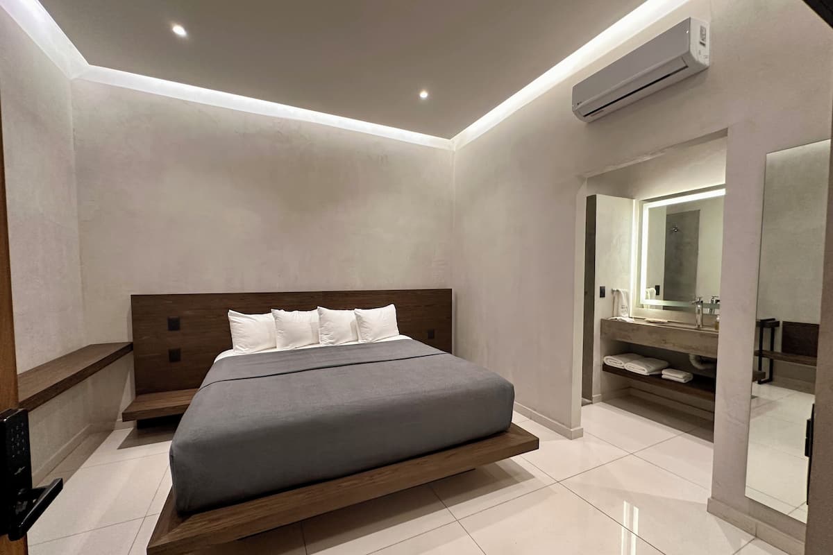 A modern bedroom with a bed, a built-in shelf, a mirror, and an air conditioning unit.