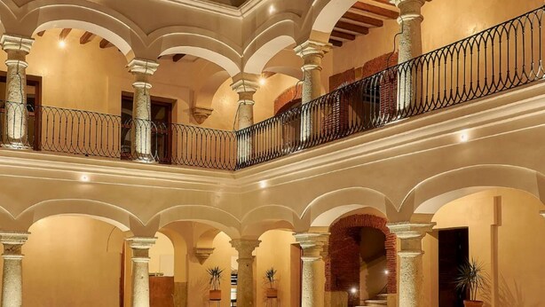 A spacious atrium with multiple arches, a central staircase, and a balcony with a wrought iron railing. - Casa Quiote Hotel Boutique City Center based - Adults Only (Oaxaca)