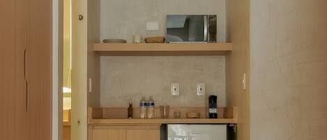 A compact kitchen with wooden cabinets, a microwave, and a refrigerator.
