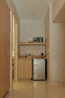 A compact kitchen with wooden cabinets, a microwave, and a refrigerator.