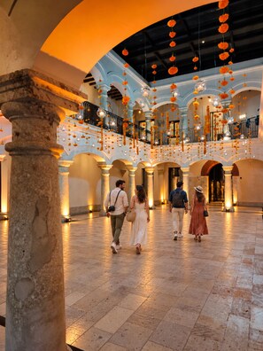 Um interior espaçoso com teto alto, colunas em arco e uma escadaria central.