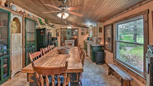 A rustic kitchen with a wooden table, chairs, and a ceiling fan.