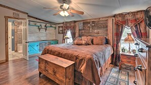 A rustic bedroom with a wooden bed, a ceiling fan, and a view of the outdoors.