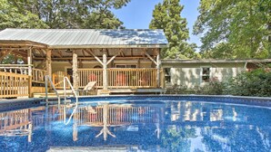A swimming pool with a wooden deck and a covered seating area.
