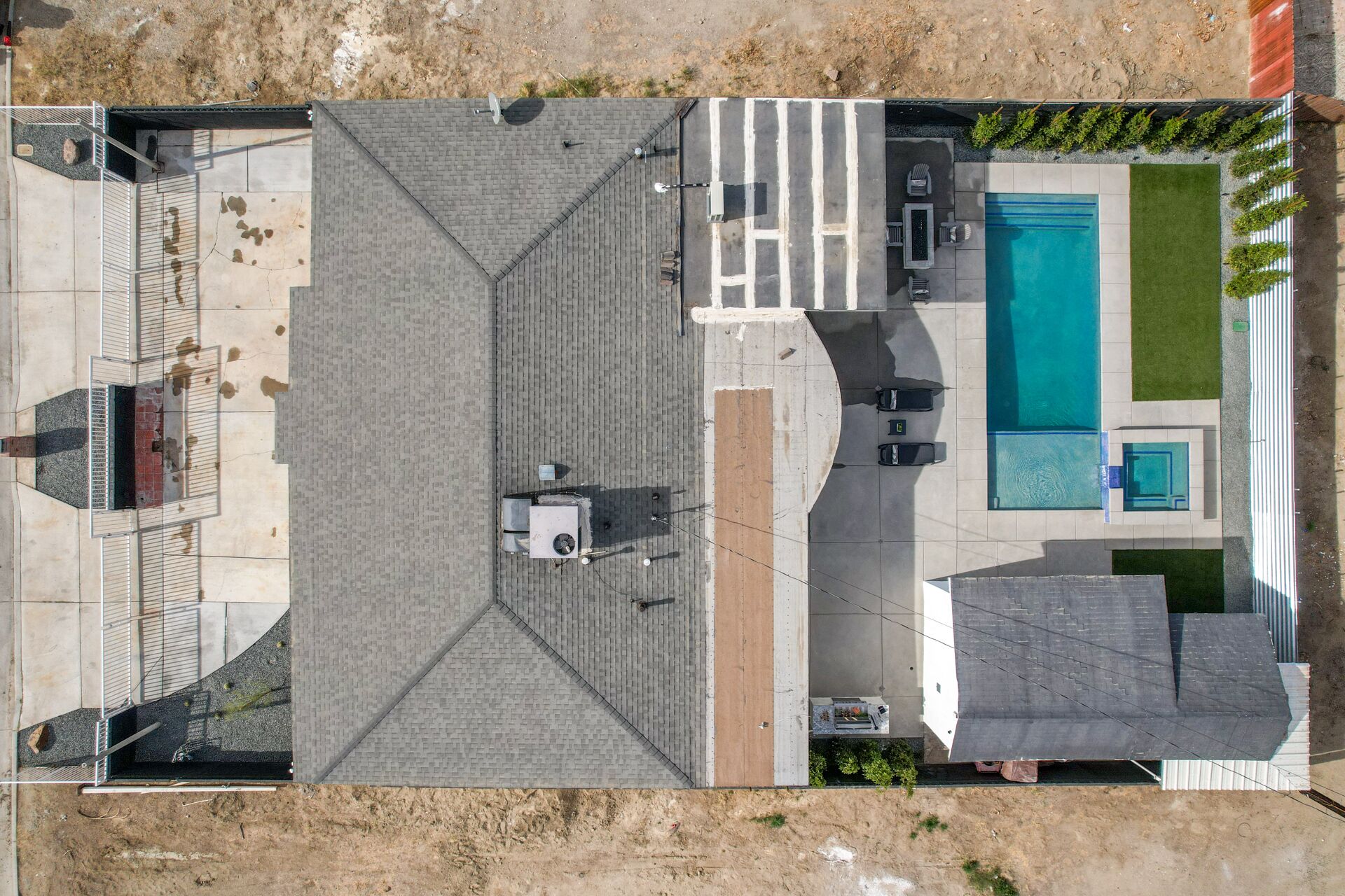 Luchtbeeld van een woonhuis met een zwembad, terrasmeubilair en een overdekt buitengebied.