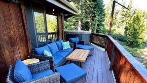 Een overdekt terras met rieten meubels en een houten tafel.