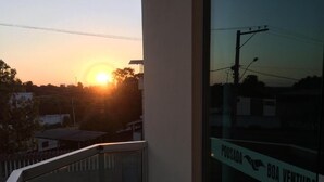 A balcony with a glass railing overlooking a sunset. A sign on the glass reads "POUSADA BOA VENTURA". - Pousada Boa Ventura (Anchieta)