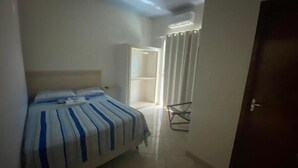 A bedroom with a bed, a chair, and a door. - Pousada Boa Ventura (Anchieta)