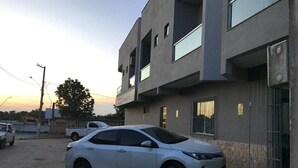 A modern building with a white car parked in front. - Pousada Boa Ventura (Anchieta)