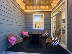A covered patio area with gray siding, a table with chairs, and string lights. - Modern Townhome- downtown Coeur d'Alene- minutes to waterfront restaurants shops (Coeur d'Alene)