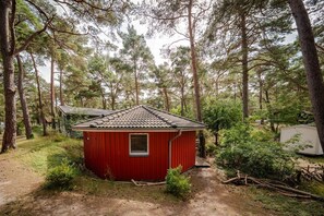 A small red cabin with a tiled roof, surrounded by dense forest. - Vacation home Tipi 365 - vacation home near the beach with terrace - Holiday home Tipi (Göhren)