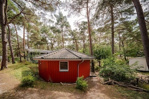 A small red cabin with a tiled roof, surrounded by dense forest. - Tipi 365 Vacation Home - Beachfront vacation home with a terrace - Tipi Vacation Home (Göhren)
