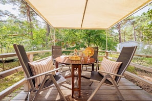 An outdoor deck with a round table, two chairs, and a canopy.