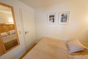 Ein Schlafzimmer mit einem Bett, einem Spiegel und zwei gerahmten Bildern an der Wand.