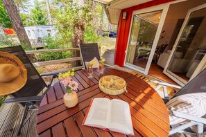 A wooden deck with a table, chairs, a book, a hat, and a basket of snacks. - Vacation home Tipi 365 - vacation home near the beach with terrace - Holiday home Tipi (Göhren)