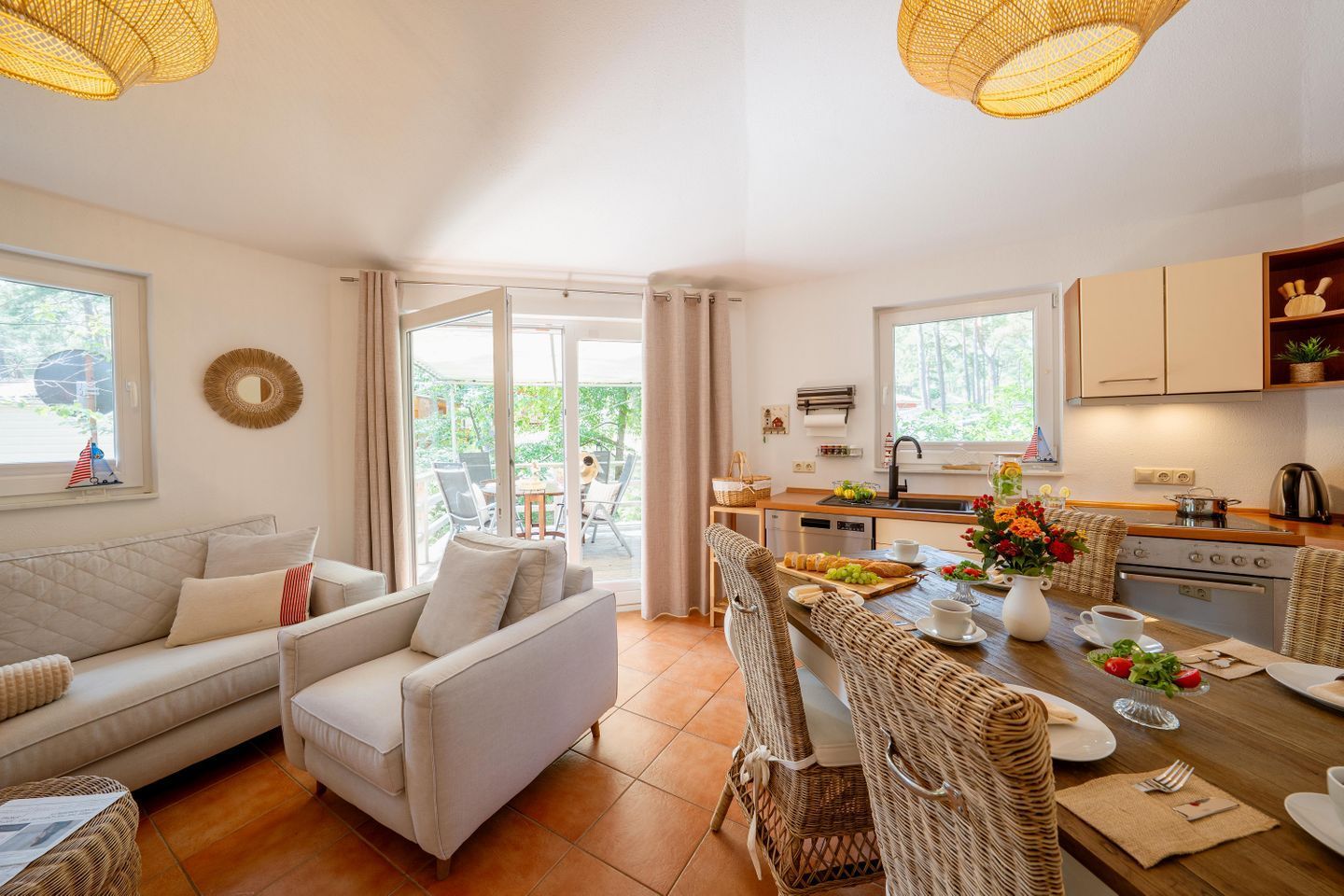 A cozy living area with a sofa and chairs, a dining table set with plates and cups, and a kitchen with cabinets and a sink.