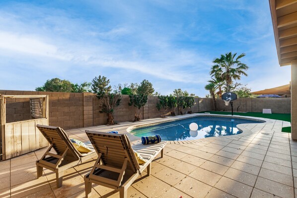 A pool area with lounge chairs and a brick wall. - 4BR w pool, yard for games, bonus office! (Gilbert)