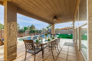 A covered patio with a pool, outdoor dining set, and a view of the backyard. - 4BR w pool, yard for games, bonus office! (Gilbert)