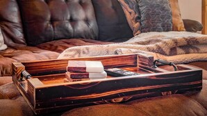 Un plateau en bois avec une télécommande et des livres, posés sur un canapé en cuir marron.